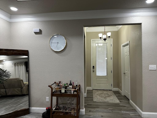 entryway featuring hardwood / wood-style floors, crown molding, and an inviting chandelier