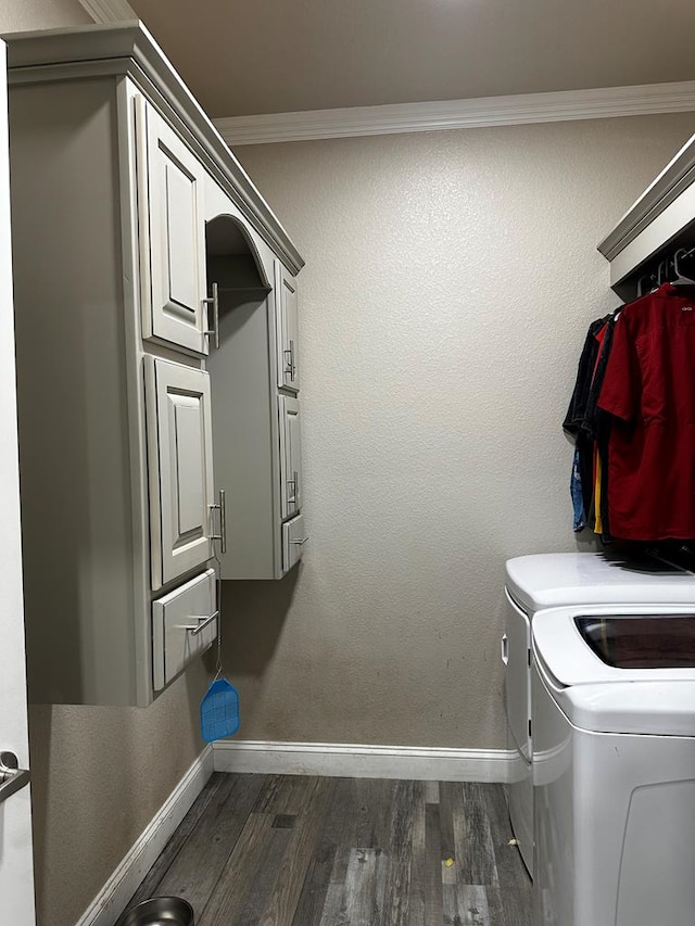 clothes washing area featuring cabinets, dark hardwood / wood-style flooring, ornamental molding, and washing machine and clothes dryer