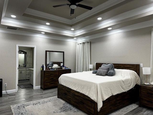 bedroom with light wood-type flooring, ensuite bathroom, ornamental molding, a raised ceiling, and ceiling fan