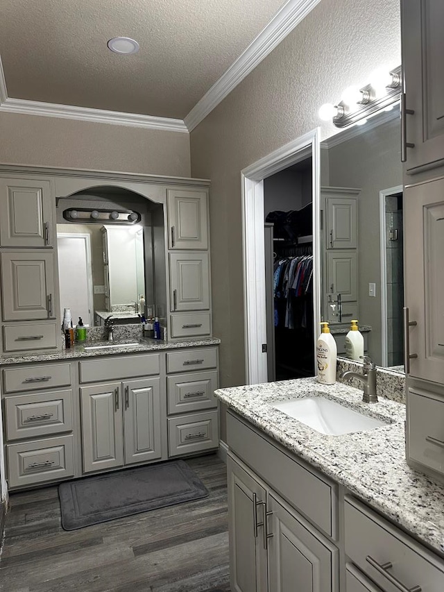 bathroom featuring a textured ceiling, vanity, wood-type flooring, and ornamental molding