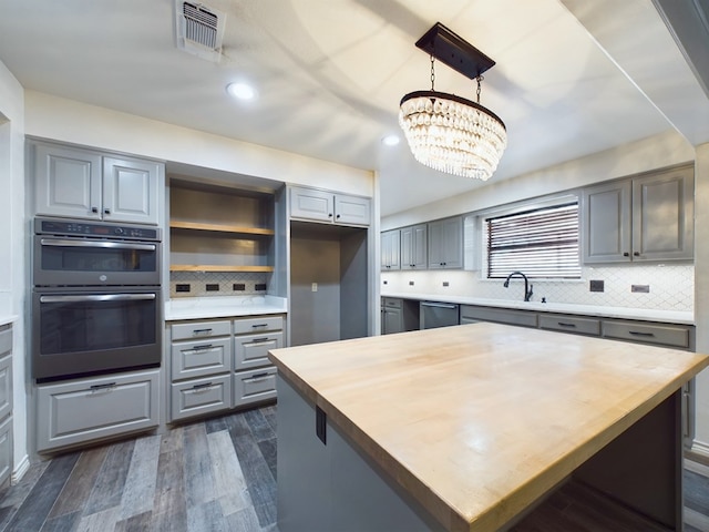 kitchen featuring double oven, gray cabinetry, dark wood-type flooring, and a notable chandelier