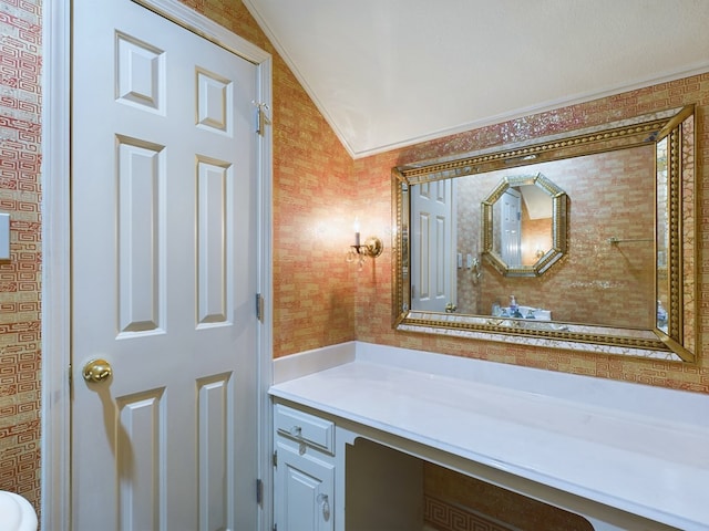 bathroom featuring vanity, lofted ceiling, and crown molding