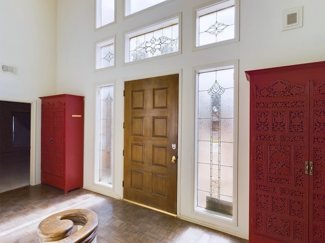 foyer with parquet floors, a wealth of natural light, and a towering ceiling