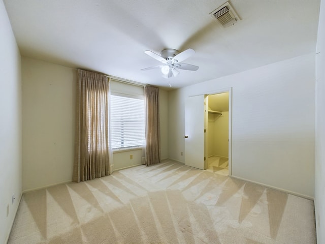 unfurnished bedroom featuring ceiling fan, a closet, light colored carpet, and a spacious closet