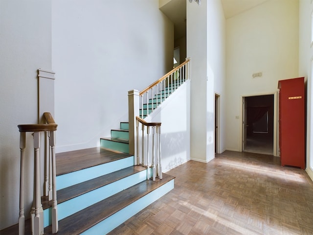 staircase with a high ceiling and parquet floors