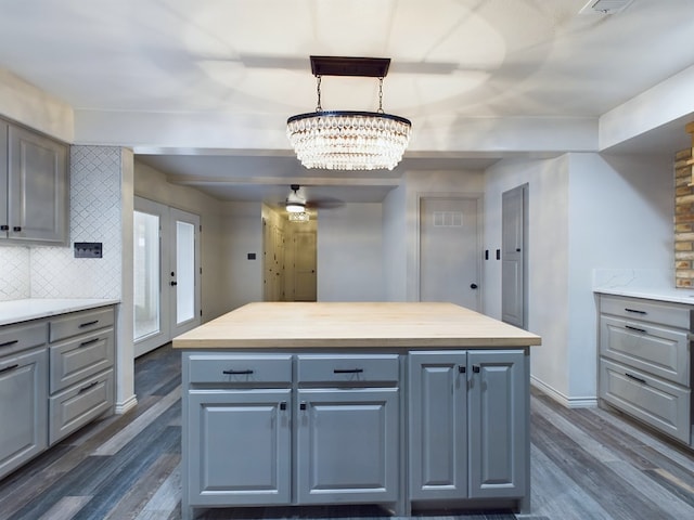 kitchen featuring dark hardwood / wood-style flooring, tasteful backsplash, decorative light fixtures, a kitchen island, and butcher block counters