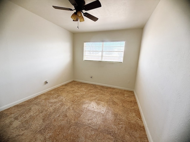 spare room featuring a ceiling fan and baseboards