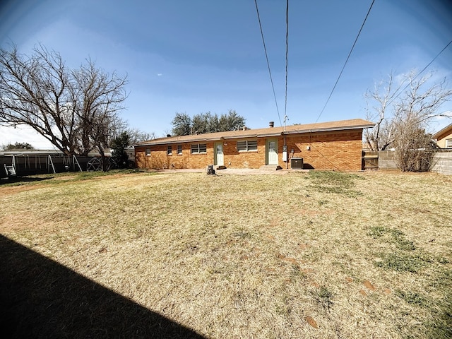 back of house with a yard, fence, and brick siding