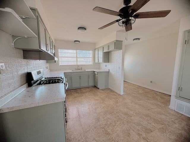 kitchen with decorative backsplash, light countertops, stainless steel range with gas cooktop, and gray cabinetry