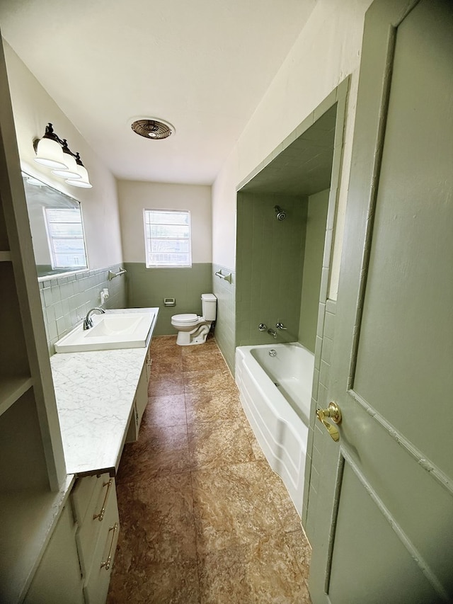 full bathroom with vanity, a wainscoted wall, shower / washtub combination, tile walls, and toilet