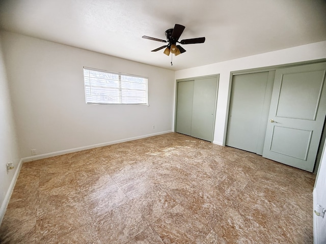 unfurnished bedroom featuring baseboards, two closets, and ceiling fan