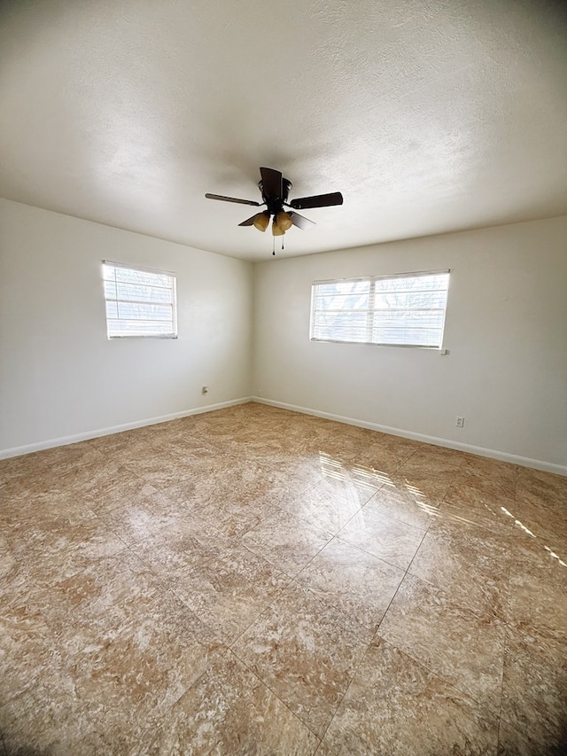 unfurnished room with baseboards, a textured ceiling, and a ceiling fan