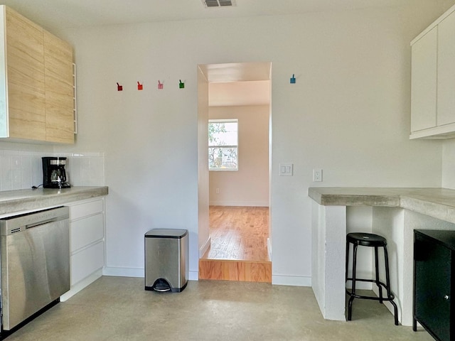 kitchen with tasteful backsplash, white cabinetry, dishwasher, and light hardwood / wood-style floors