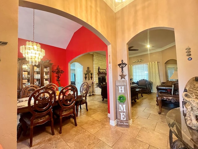 dining space featuring a brick fireplace, a chandelier, a high ceiling, and ornamental molding