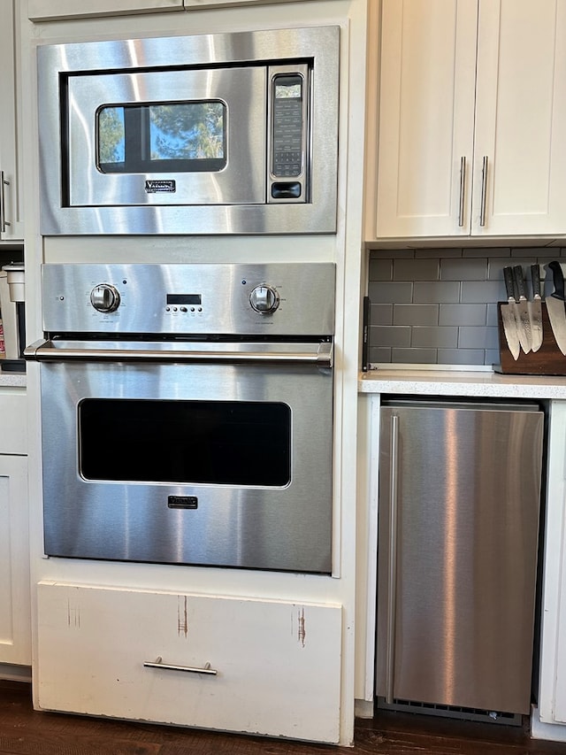 kitchen with white cabinetry, decorative backsplash, dark hardwood / wood-style flooring, and stainless steel appliances