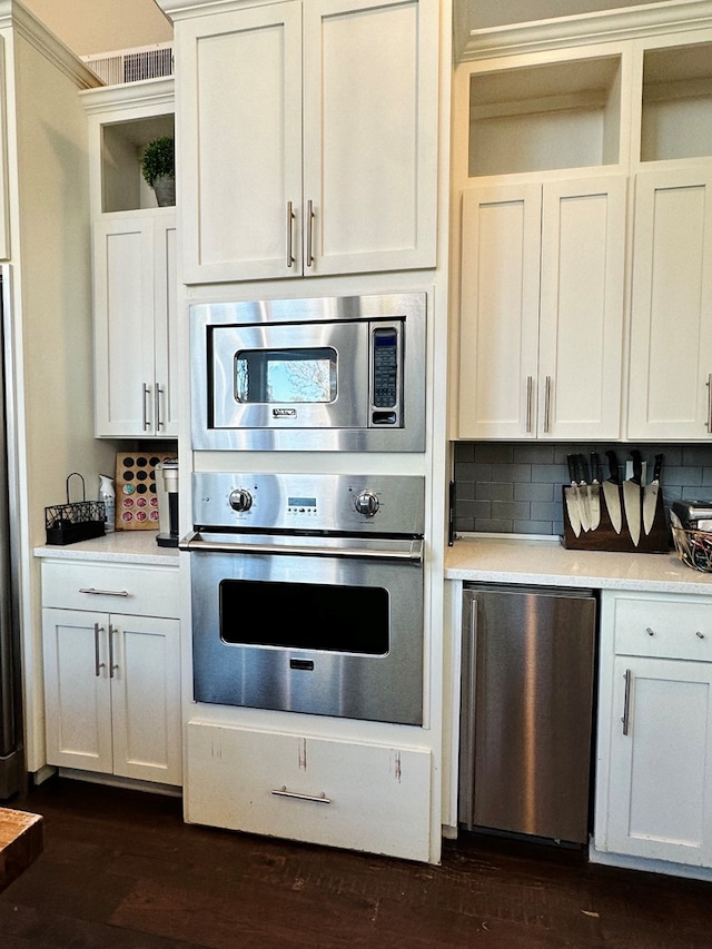 kitchen featuring stainless steel appliances, decorative backsplash, and white cabinets