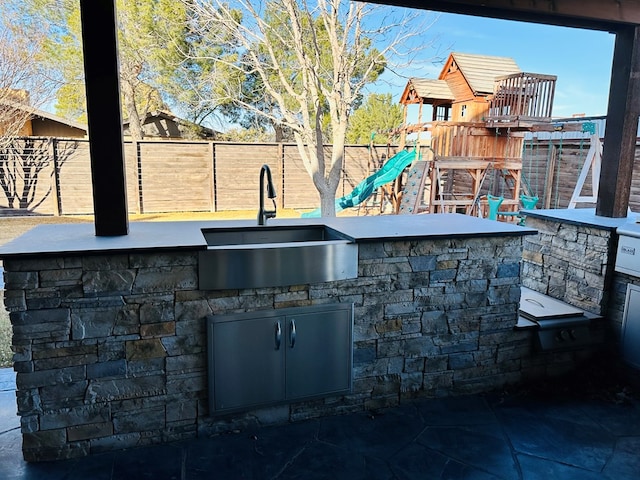 view of patio with an outdoor kitchen, a playground, and an outdoor wet bar