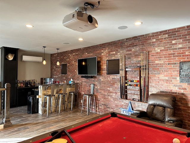 game room featuring hardwood / wood-style flooring, brick wall, bar, and a wall unit AC