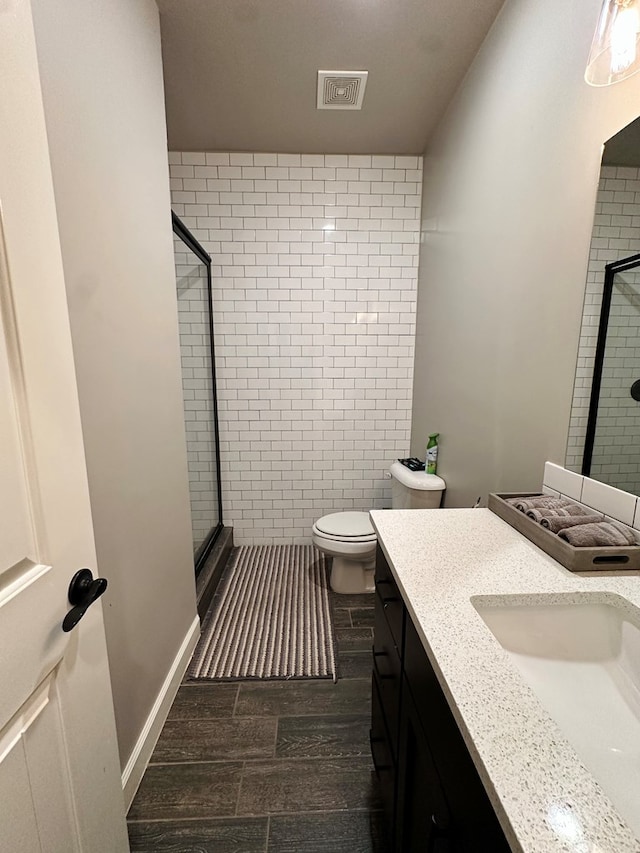 bathroom featuring vanity, toilet, and a shower with shower door