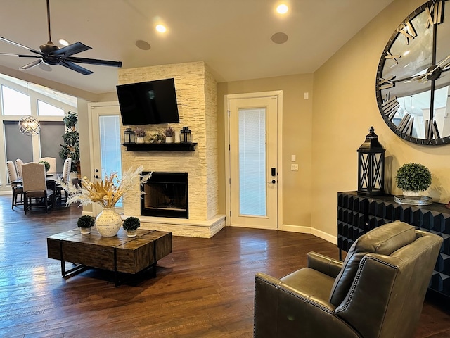 living room with a stone fireplace, dark hardwood / wood-style floors, lofted ceiling, and ceiling fan