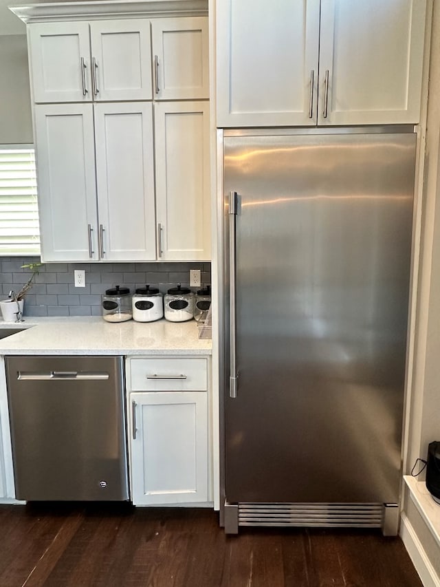 kitchen with stainless steel appliances, light stone countertops, white cabinets, and dark hardwood / wood-style flooring