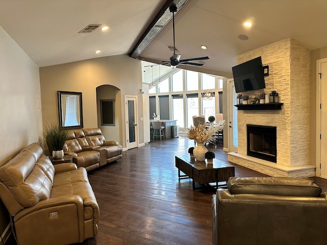 living room featuring a stone fireplace, high vaulted ceiling, dark hardwood / wood-style flooring, beamed ceiling, and ceiling fan