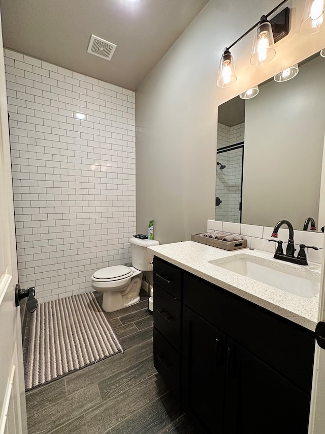 bathroom featuring vanity, toilet, and tiled shower