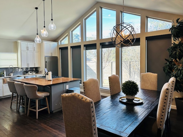 dining area with a notable chandelier, sink, high vaulted ceiling, and dark hardwood / wood-style floors