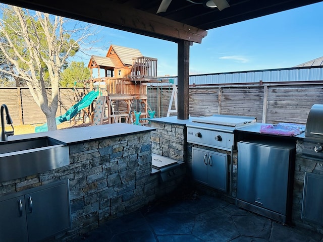 view of patio / terrace featuring sink, a playground, and an outdoor kitchen