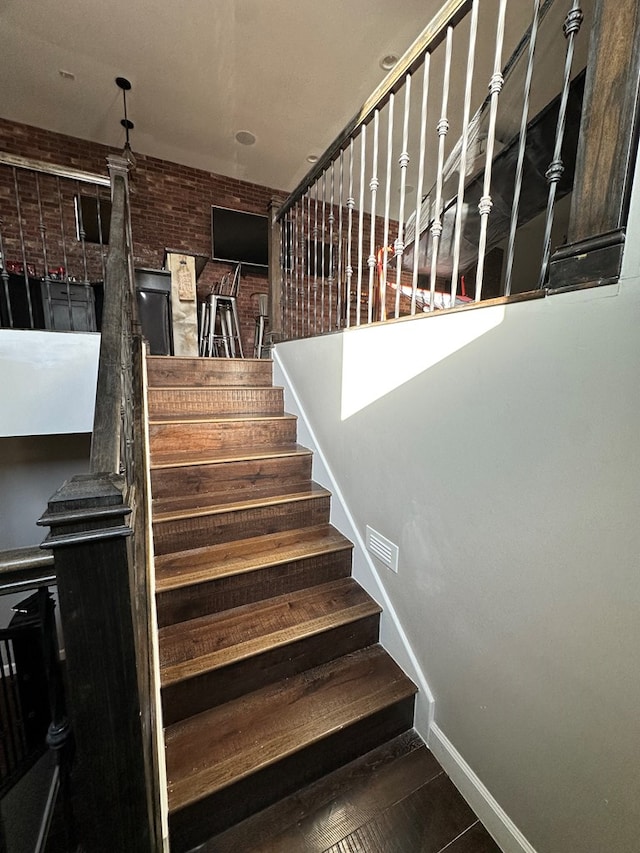 staircase featuring brick wall