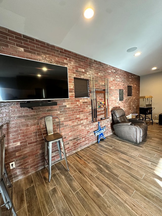 living room featuring hardwood / wood-style flooring and brick wall