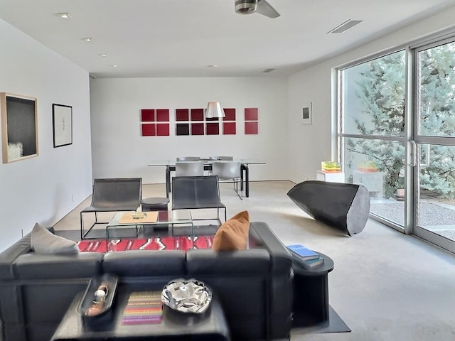 living room featuring plenty of natural light, ceiling fan, and concrete floors