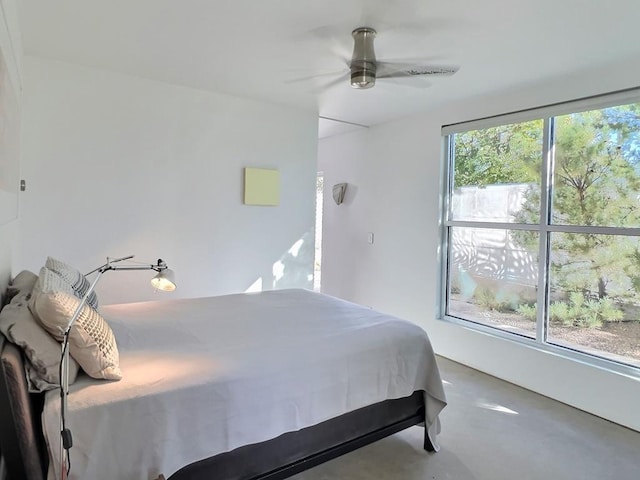 bedroom with multiple windows, ceiling fan, and concrete flooring