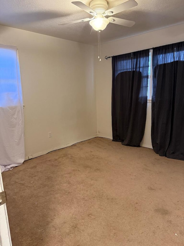 empty room with a ceiling fan, a textured ceiling, and light colored carpet