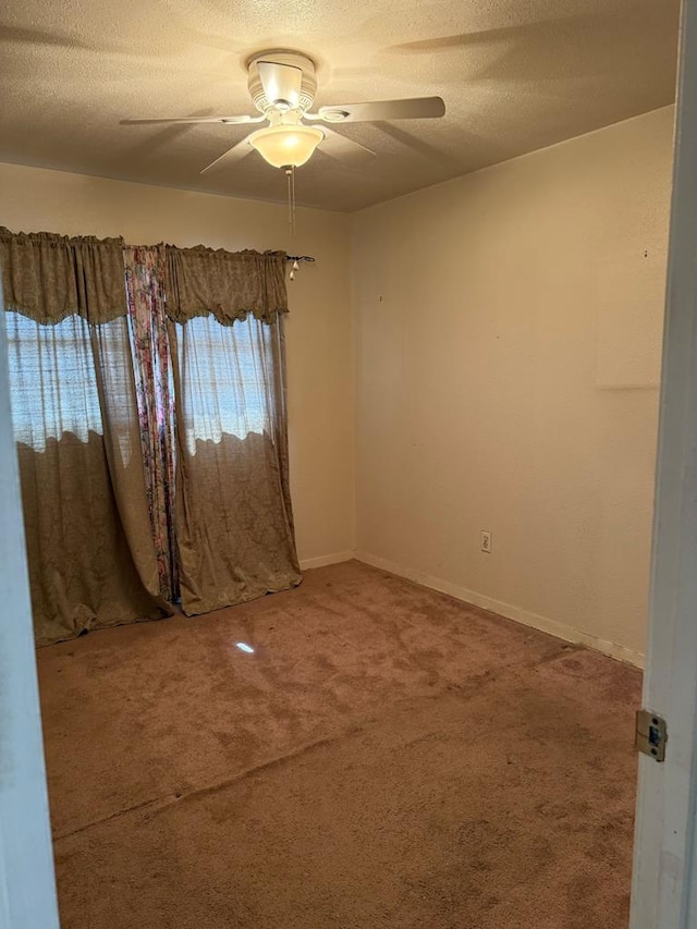 spare room with carpet, ceiling fan, a textured ceiling, and baseboards