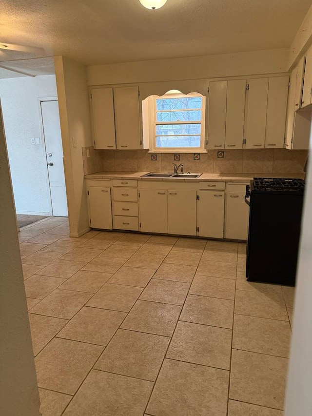 kitchen with light countertops, backsplash, light tile patterned flooring, and a sink