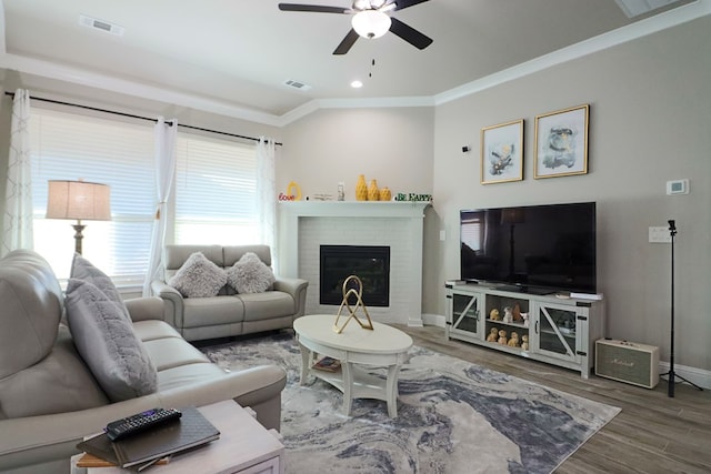 living area with wood finished floors, baseboards, visible vents, a fireplace, and ceiling fan