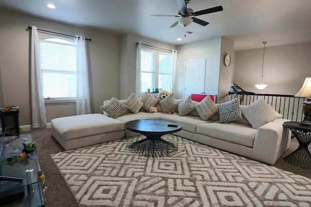 living area featuring visible vents, carpet floors, a healthy amount of sunlight, and a ceiling fan