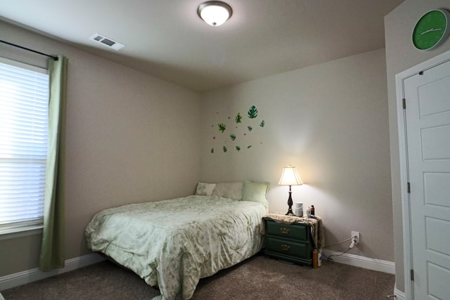 bedroom featuring visible vents, multiple windows, dark carpet, and baseboards