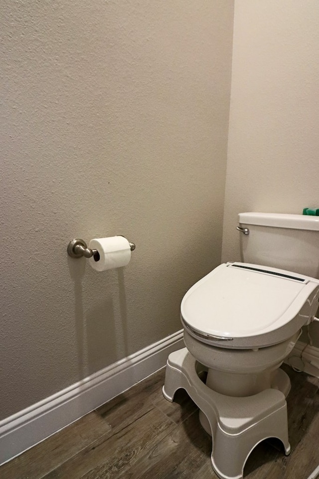 bathroom featuring toilet, baseboards, and wood finished floors