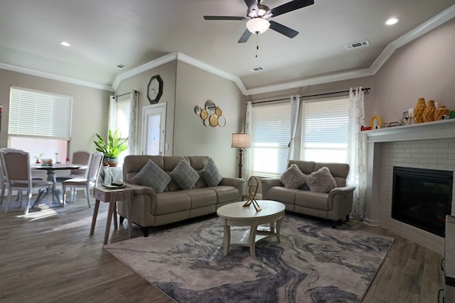 living room featuring visible vents, plenty of natural light, wood finished floors, and ornamental molding