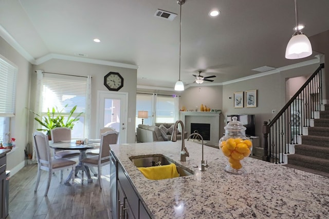 kitchen featuring visible vents, ornamental molding, a sink, open floor plan, and ceiling fan