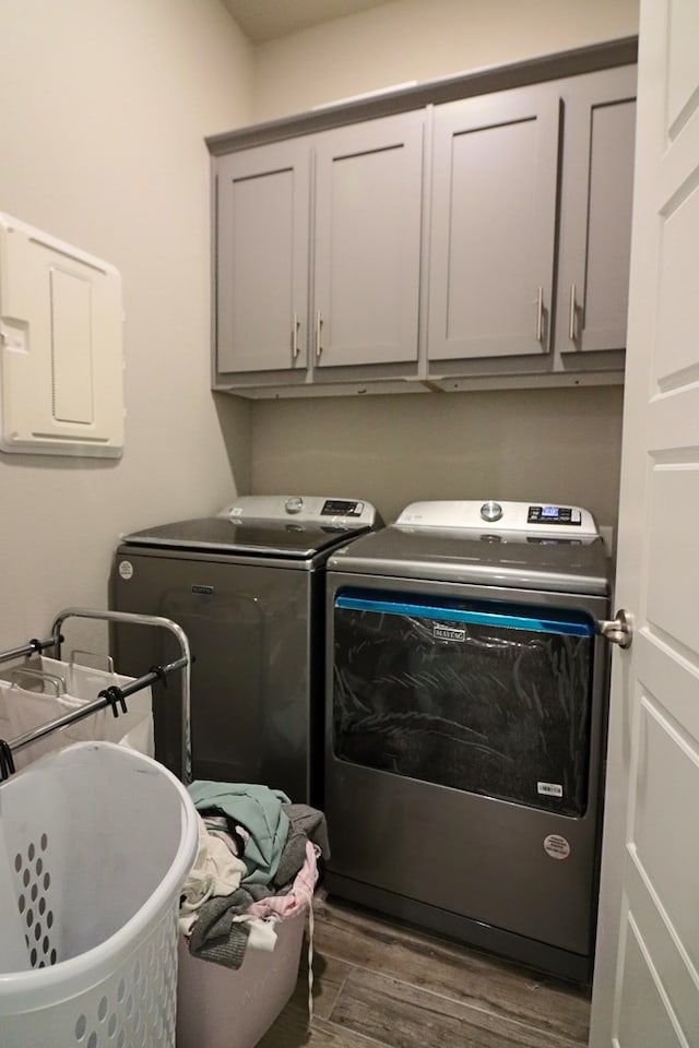 laundry area featuring dark wood-style floors, cabinet space, and separate washer and dryer