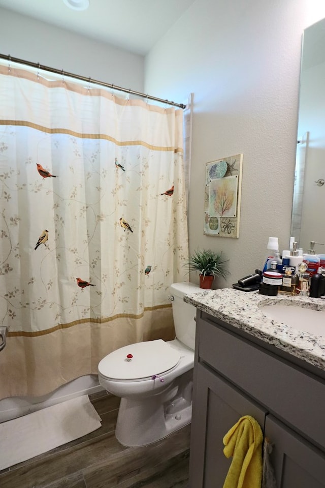 full bath featuring toilet, curtained shower, vanity, and wood finished floors