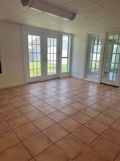 tiled empty room featuring french doors