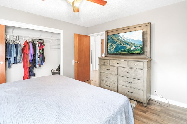 bedroom with a textured ceiling, light hardwood / wood-style floors, a closet, and ceiling fan