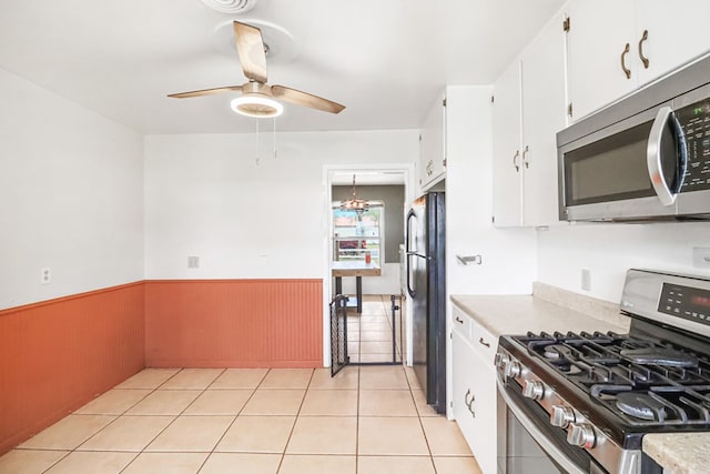 kitchen with white cabinets, ceiling fan with notable chandelier, stainless steel appliances, and light tile patterned flooring