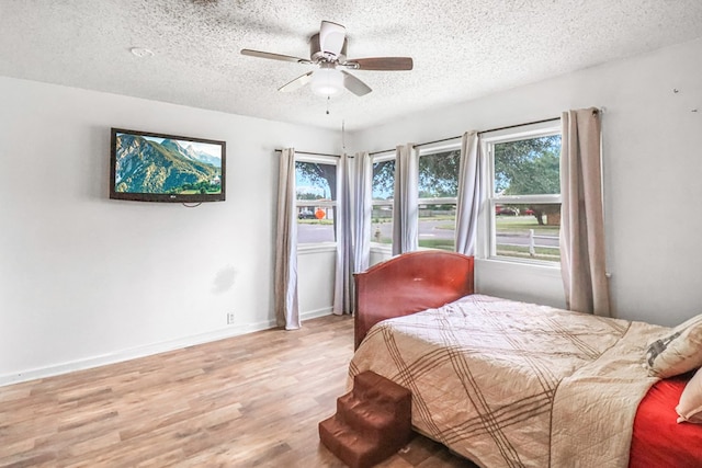 bedroom with ceiling fan, light wood-type flooring, and a textured ceiling