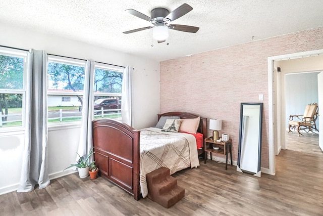 bedroom with a textured ceiling, ceiling fan, and dark hardwood / wood-style floors