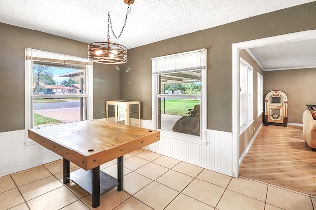 dining space with a textured ceiling, light hardwood / wood-style floors, a wealth of natural light, and a notable chandelier